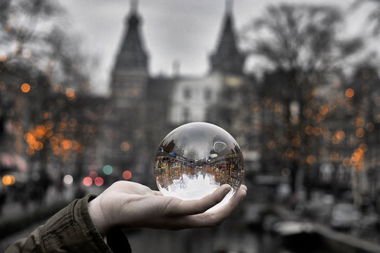 Person holding photography sphere creating a mirrored upside down image of Amsterdam canal with historic rijksmuseum in the background