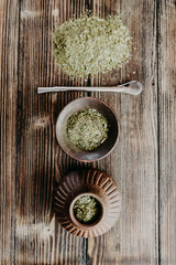 A yerba mate tea set of calabash gourd, ceramic cup, bombilla and grounded tea leafs on the wooden background. Flat lay, top view. Shallow focus. Vertical orientation.