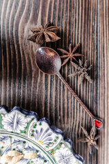Authentic middle east style bronze spoon with a cinnamon on the wooden desk with a colourful eastern plate. Flat lay, top view. Vertical orientation.