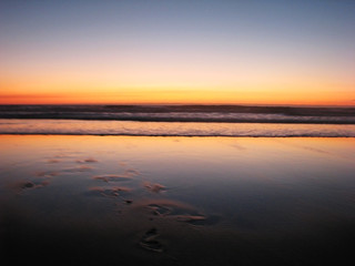 Dark blurred sunset on the sandy shore of the ocean.
