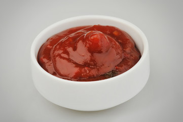 Small one bowl of red tomato sauce ketchup isolated on gray background