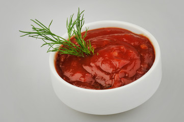 Small one bowl of red tomato sauce ketchup and dill isolated on gray background