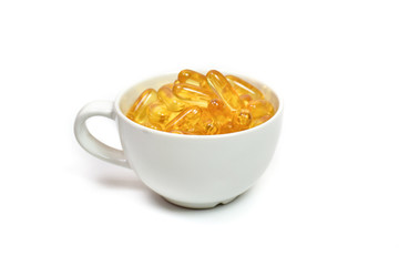 Supplementary food for good health. Gold fish oil in cup isolated on white background. Supplementary food. Omega 3. Vitamin E. Capsules salmon fish oil.
