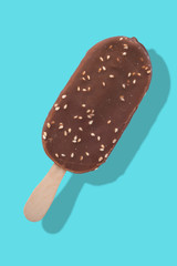 Chocolate ice cream on a stick with nuts on a blue background with a reflection separation.