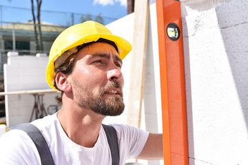 Bauarbeiter prüft mit Waqsserwage beim Hausbau // profession construction worker - work on a building site construction of a residential house