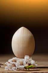 wooden easter eggs among flowering cherry branches on a rustic table. symbolic composition of the spring holiday for a gift card. copy space. close up. petals of white flowers. the rebirth of nature