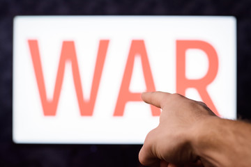 Young male pointing to a screen with inscription WAR to draw our attention to circumstances that different conflicts between countries can lead