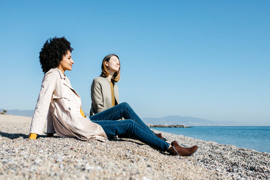 Two friends sitting on the beach enjoying leisure time