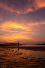 Fototapeta na wymiar Silhouette of a man on the background of a golden dawn on the beach of Sanya, Hainan Island, China