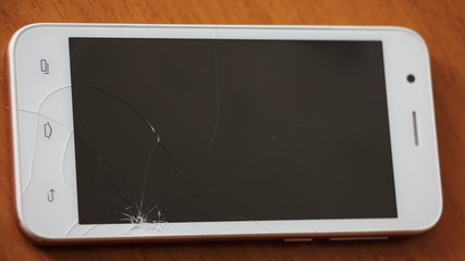 Close up white smartphone with a damaged screen with cope space on a brown table, repair electronics