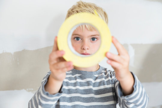 Portrait of boy looking through sticky tape toll