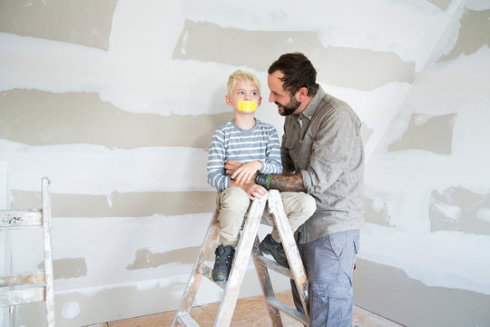 Father looking at son on ladder with taped mouth