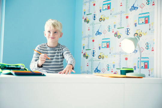 Smiling boy doing homework at desk in children's room