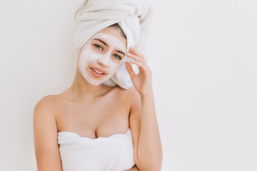 Portrait of beautiful young woman with towels after take bath make cosmetic mask on her face. Rejuvenation, cosmetology,hydration and care face. Clean and perfect skin. Spa treatments.White background