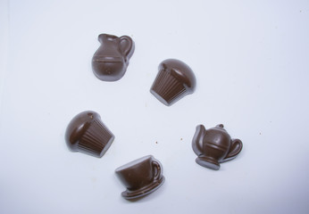 handmade chocolates sweets in the shape of cups, cake and teapot on white background