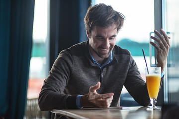 Handsome middle aged man with positive expression using phone in a cafe bar