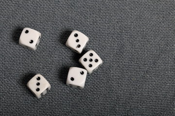 White dice with black markings. They lie on a surface covered with a coarse gray cloth. View from above.