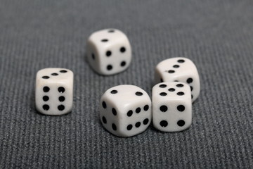 White dice with black markings. Lie on a surface covered with a coarse gray cloth
