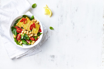 Chickpea, spinach and cherry tomato salad with fried tofu.  Flat lay. Copy space. Vegan food