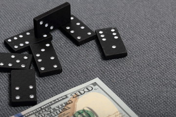 Domino knuckles on a surface covered with a coarse gray cloth. Nearby is a hundred dollar bill.