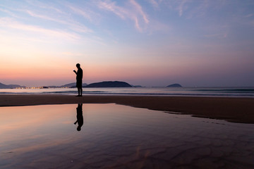 Venus and the silhouette of a man and their reflection on the background of the dawn on the beach of Sanya, Hainan Island, China