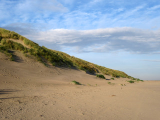 North sea dunes on Vlieland, a Dutch Wadden Island in the Wadden Sea. With blue sky and white clouds above the dune.