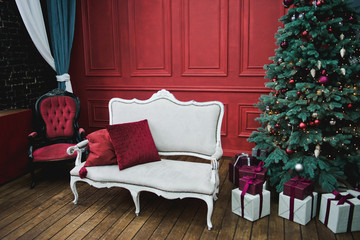 Beautiful New Year decorated classic home interior. Winter background. Living room with a Christmas decor. Holiday background. New Year's decorations. White sofa against the red wall.