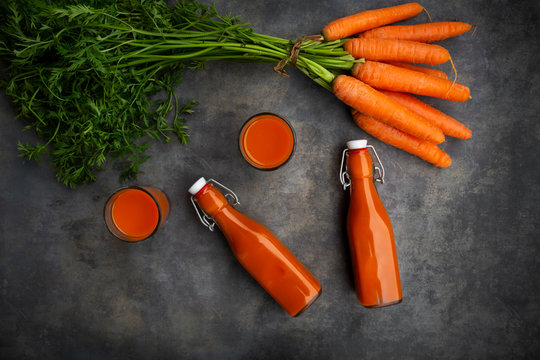 Carrot juice in bottles and glasses, bunch of carrots, from above