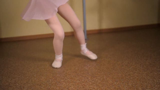 ittle ballerina in a white suit and pink skirt is engaged in a dance class
