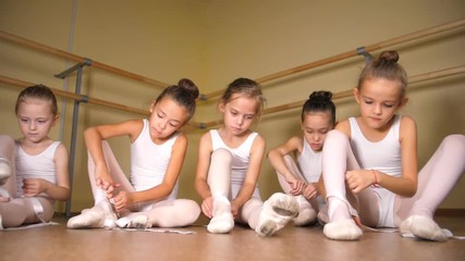 Young Ballerinas Getting Ready For Practice.  Little ballerina tying pointe shoes