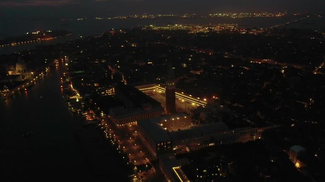 Aerial drone night video of iconic illuminated Saint Mark's square or Piazza San Marco featuring Doge's Palace, Basilica and Campanile, Venice, Italy