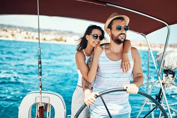 Fototapeten Romantic couple on a yacht enjoy bright sunny day on vacation. © luckybusiness