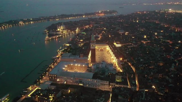 Aerial drone night video of iconic illuminated Saint Mark's square or Piazza San Marco featuring Doge's Palace, Basilica and Campanile, Venice, Italy