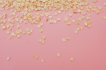 Fun healthy food, the concept. Grain oatmeal on a pink background. Oat flakes scattered