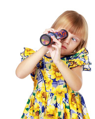 A little girl looks into a telescope or in a kaleidoscope.