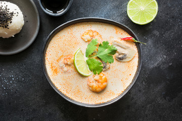 Tom yam kung spicy thai soup with shrimp, seafood, coconut milk, chili pepper and rice. View from above.