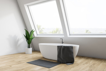 Corner of white attic bathroom with tub