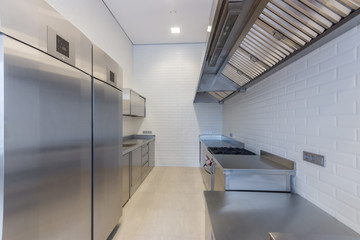 Fototapeta na wymiar Interior of professional kitchen. Work tables, sinks, cupboards and refrigerator
