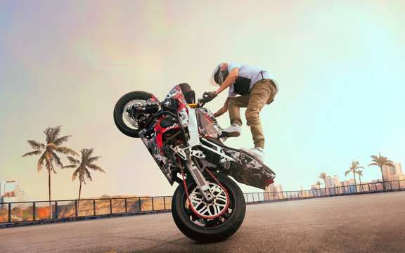 Moto rider making a stunt on his motorbike. Biker doing a difficult and dangerous stunt.