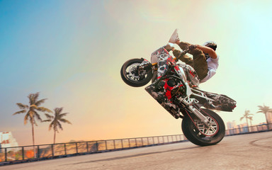 Fototapeta na wymiar Moto rider making a stunt on his motorbike. Biker doing a difficult and dangerous stunt.