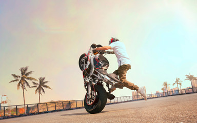 Moto rider making a stunt on his motorbike. Biker doing a difficult and dangerous stunt.