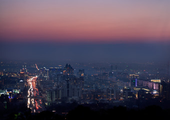 Fototapeta na wymiar Red glow after sunset over Almaty with highrise towers and Al Farabi Avenue Kazakhstan