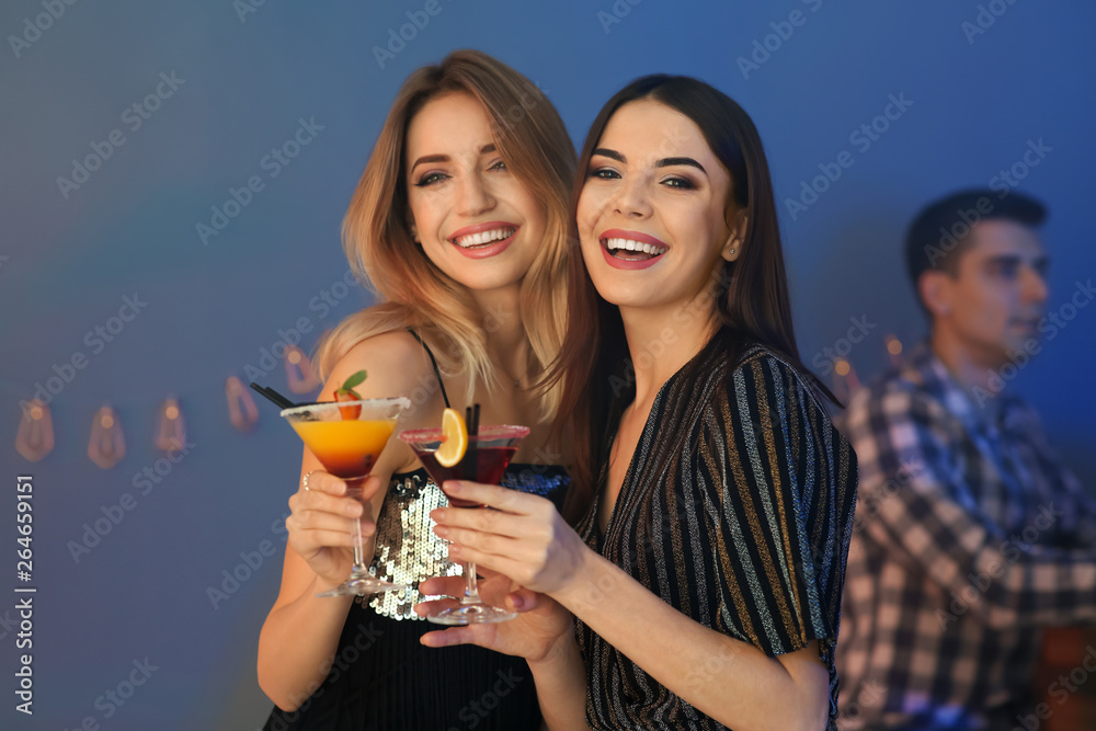 Wall mural beautiful young women with martini cocktails in bar