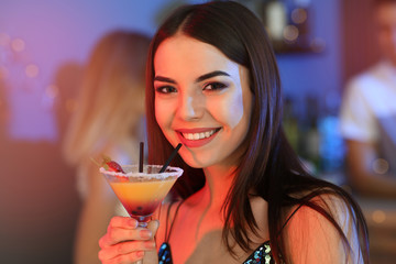 Beautiful young woman with glass of martini cocktail in bar