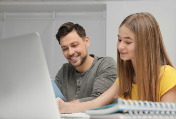 Father helping his teenager daughter with homework indoors