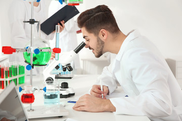 Medical student working with microscope in modern scientific laboratory