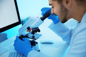Medical student working with microscope in modern scientific laboratory