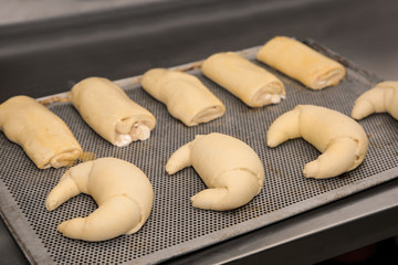 Different unbaked pastries on tray in workshop