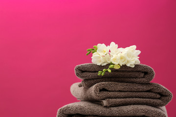 Obraz na płótnie Canvas Stack of soft clean towels with beautiful flowers on color background. Space for text