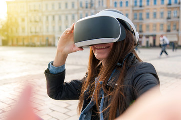 Beautiful young brunette wearing virtual reality headset in an urban context